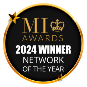 Circular black and gold badge displaying the text “MI Awards 2024 Winner – Network of the Year”, featuring a gold crown above the letters “MI” and small gold stars around the outer edge.